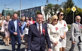 Mieszkańcy i przedstawiciele władz lokalnych uczestniczą w przemarszu ulicami miasta.