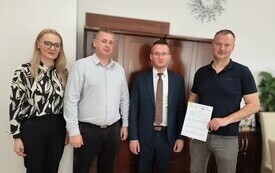 Burmiustrz, pracownik Urzędu, prezes OSP Rycice oraz Przedstawiciel Wykonawcy stoją wsp&oacute;lnie po podpisaniu umowy.