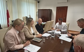 Uczestnicy spotkania siedzą przy stole podczas podpisania umowy.