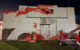 Powstający mural na ścianie budynku w Chorzelach. Widoczne są pierwsze elementy projektu przygotowanego przez młodzież.