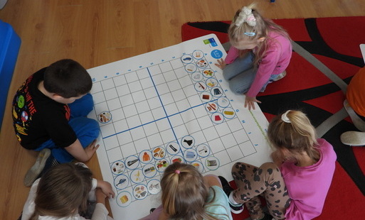 Dzieci grają przy macie edukacyjnej.