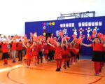 Dzieci ubrane na czerwono tańczą.