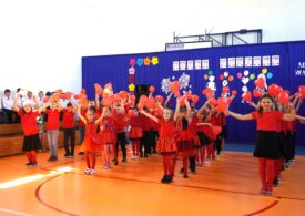 Dzieci ubrane na czerwono tańczą.