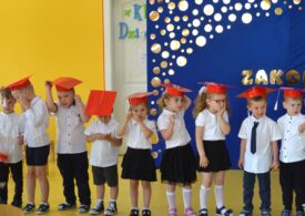 Dzieci w czerwonych czapkach absolwentów.
