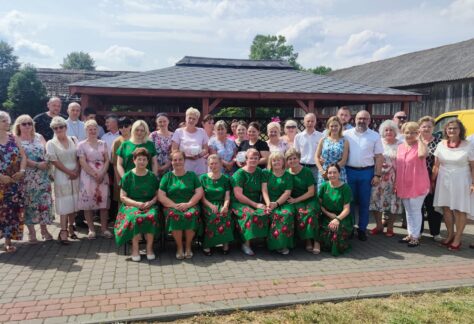 Grupa ludzi stojących przed altaną wiejską w Zdziwóju.