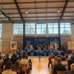 Grupa osób pozuje do zdjęcia podczas uroczystości zakończenia roku sportowego. W centrum znajdują się nagrodzeni zawodnicy trzymający dyplomy, medale lub puchary.
