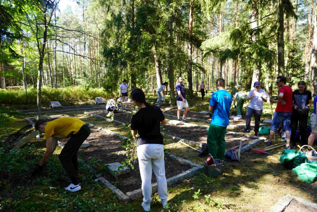 Młodzież sprząta kwaterę wojenną na cmentarzu.