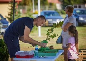 Mężczyzna trzyma sadzonkę drzewka, obok stoi kobieta i dziewczynka.